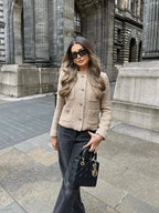 Women's beige cropped tweed jacket featuring a button front, textured fabric, and tailored fit for casual or formal wear.