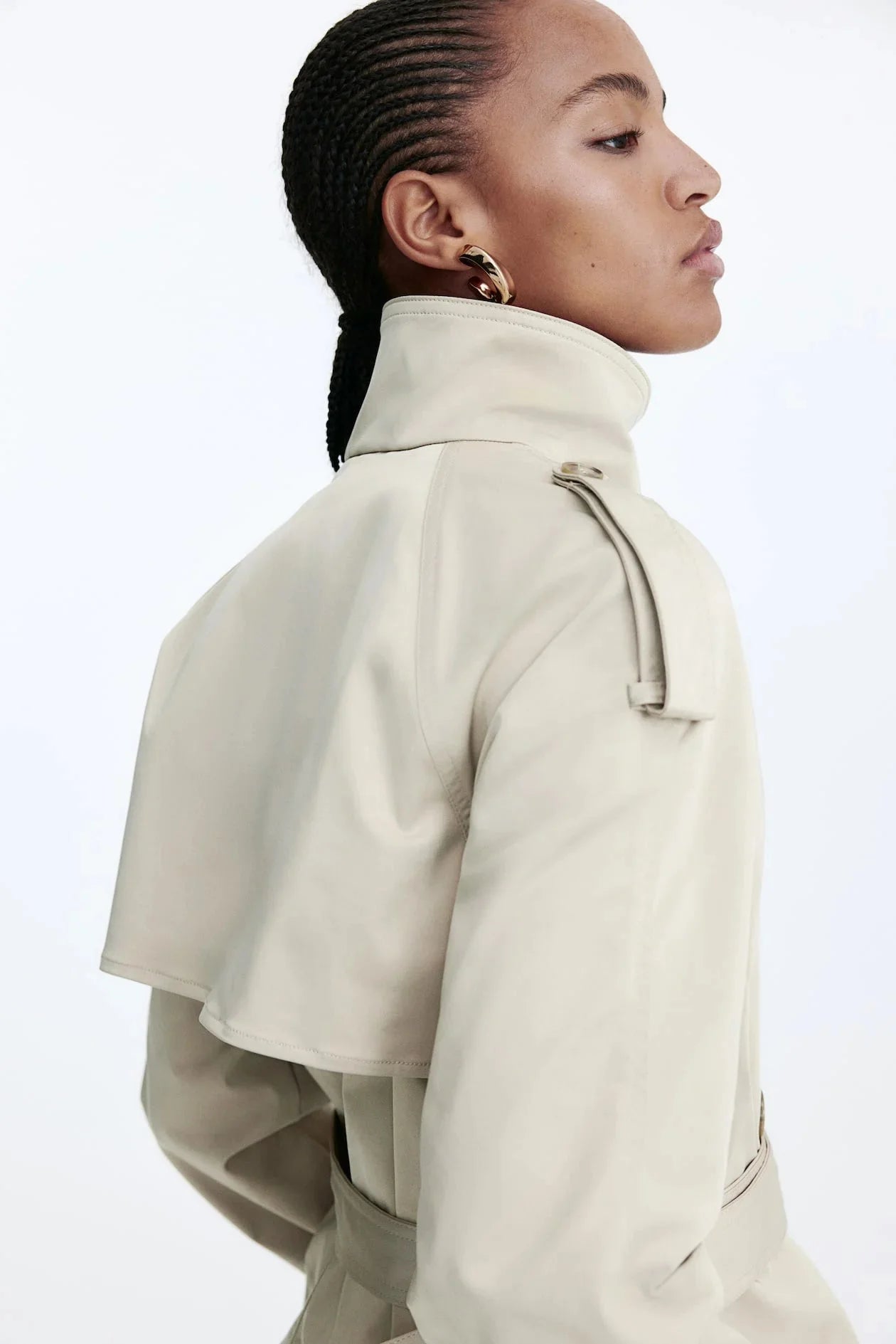 Women's beige short trench coat with belt, made from lightweight fabric, featuring a classic double-breasted design and side…
