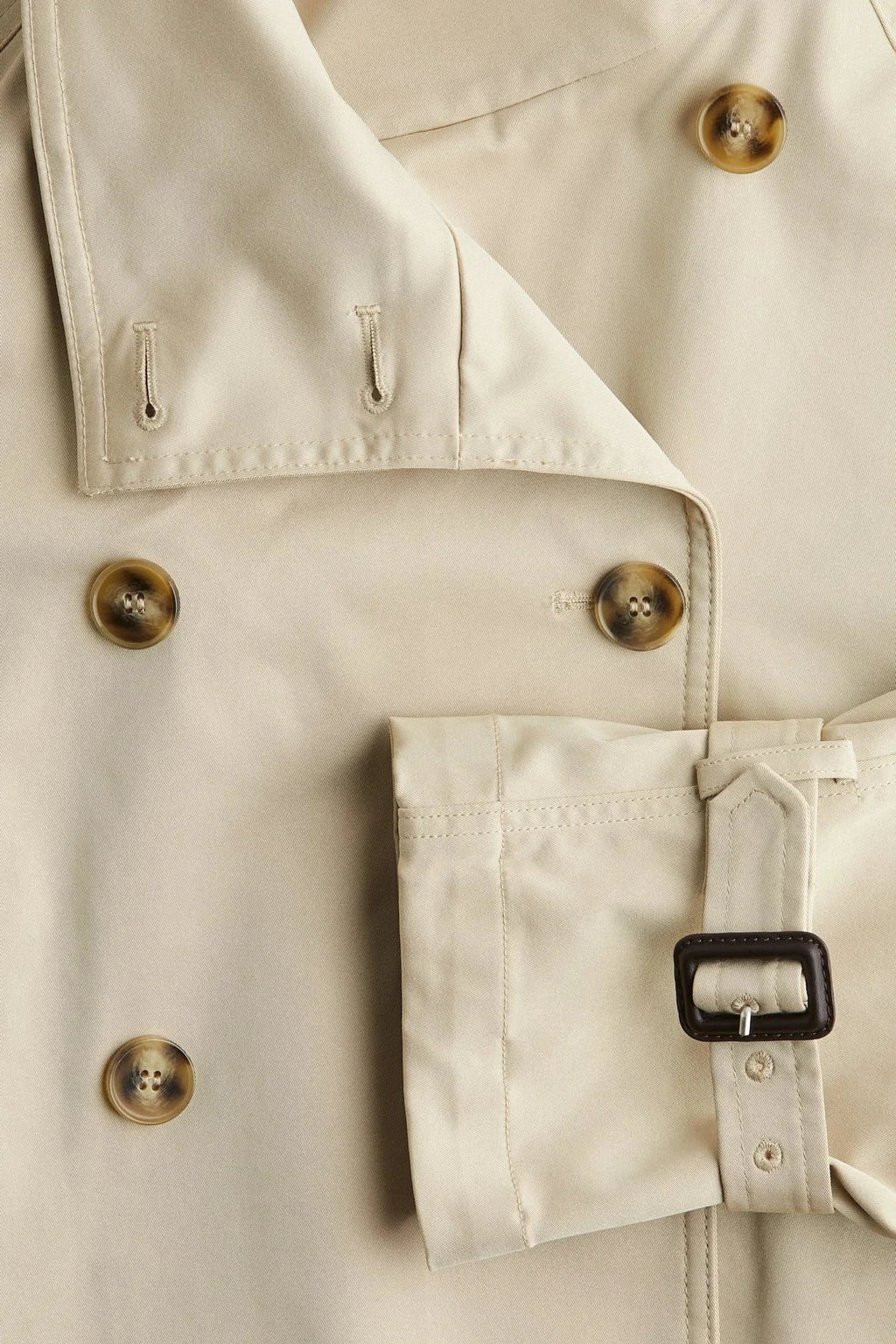 Beige short trench coat for women, featuring a belted waist, buttoned front, and lightweight fabric for versatile styling.