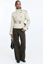 Women's beige short trench coat with belt, featuring a classic design, soft fabric, and tailored fit for versatile styling.