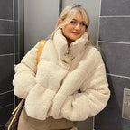 Women's beige teddy bomber coat featuring a high collar, crafted from soft, warm fabric for comfort and style in chilly…