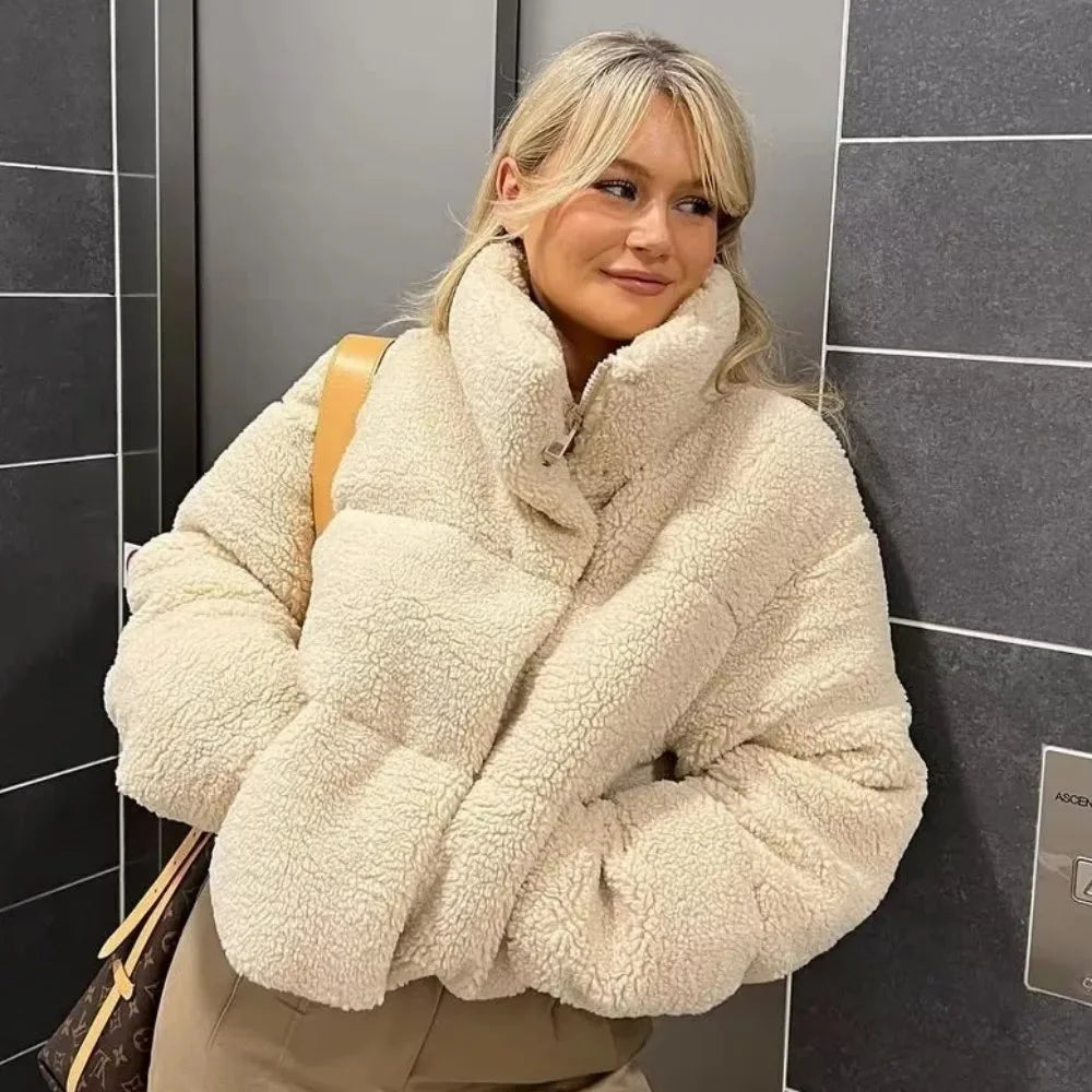 Women's beige teddy bomber coat featuring a high collar, crafted from soft, warm fabric for comfort and style in chilly…