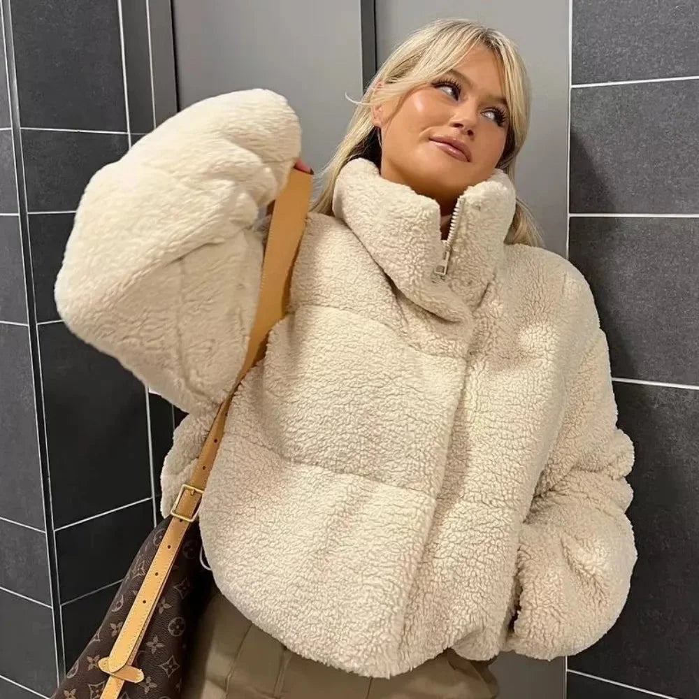 Women's beige teddy bomber coat featuring a high collar, soft faux fur fabric, and ribbed cuffs for a cozy fit.