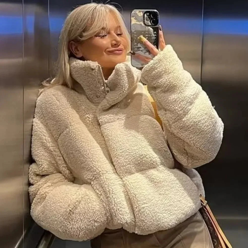 Women's beige teddy bomber coat featuring a high collar, soft texture, and ribbed cuffs for added warmth and style.