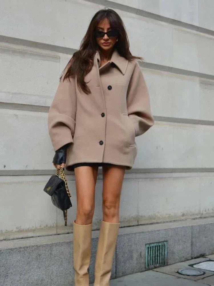 Women's beige oversized coat with a vintage-inspired design, featuring soft fabric and classic button closures.