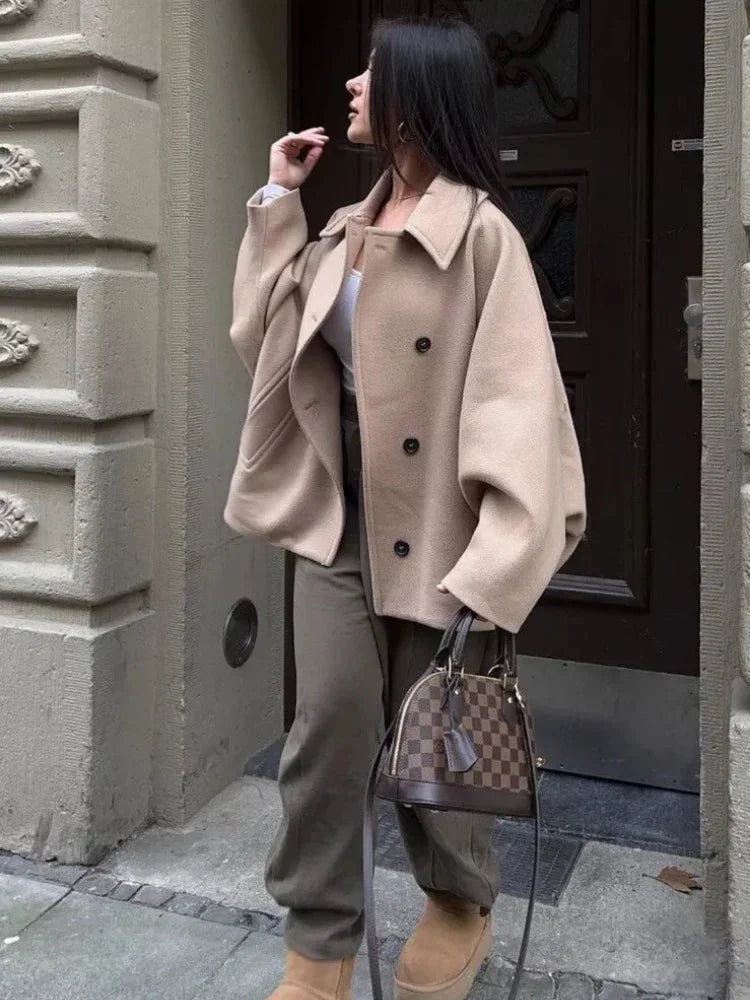 Women's beige vintage-inspired oversized coat made from soft wool blend, featuring a button-up front and large pockets.