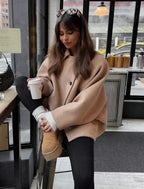 Women's beige oversized coat with a vintage-inspired design, featuring soft fabric, wide lapels, and large front pockets.
