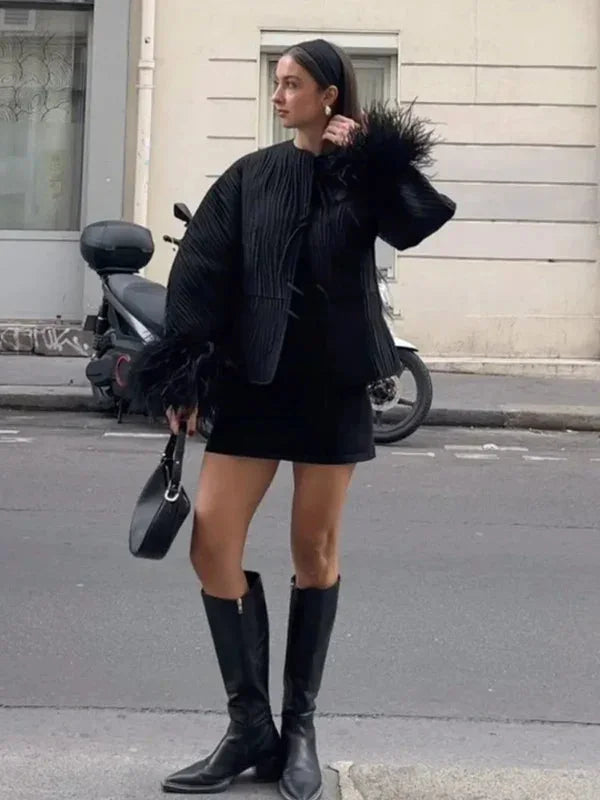 Women's black jacket featuring unique feather cuffs, crafted from soft fabric for style and comfort in cooler weather.