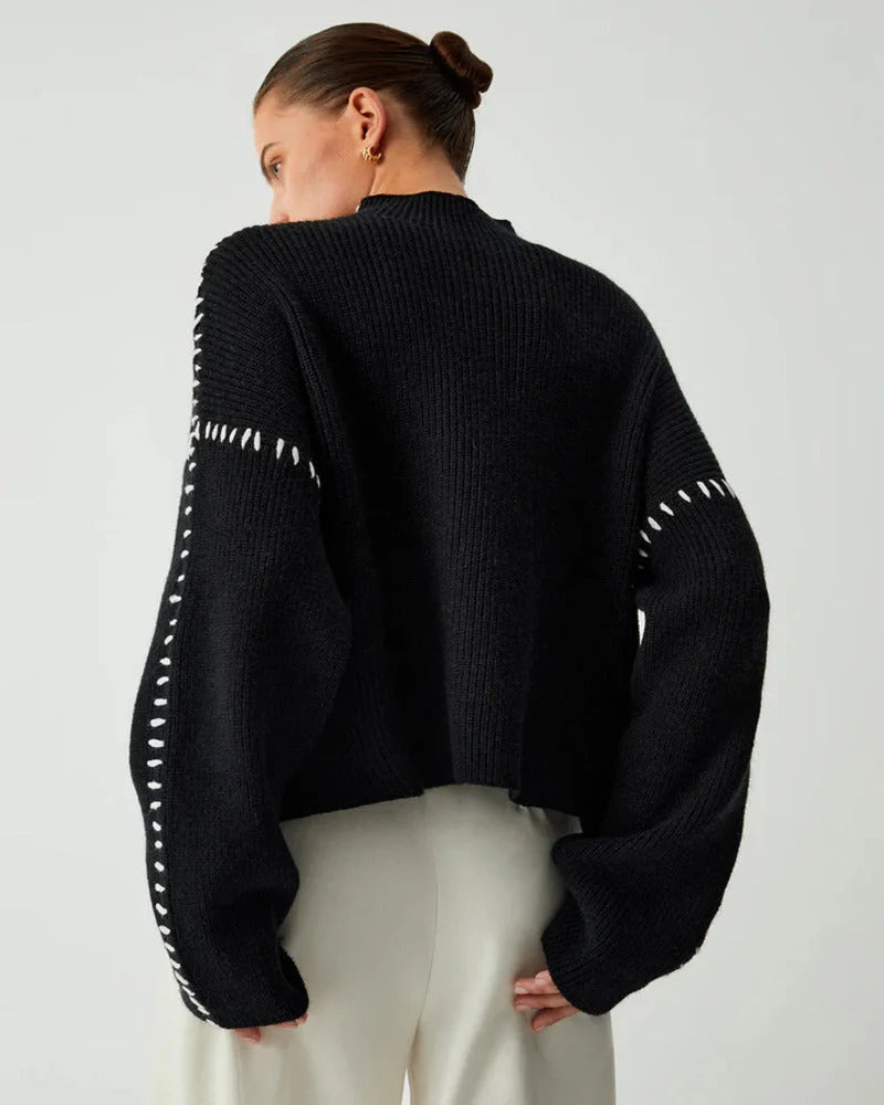 Women's black sweater made of soft fabric, featuring distinctive white stitch detailing for added visual interest.