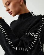 Women's black sweater featuring white stitch detail, crafted from soft cotton blend for comfort and style in everyday wear.
