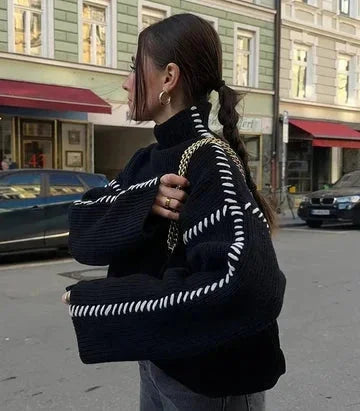Women's black sweater made from soft cotton, featuring white stitch detail along the seams for a stylish touch.