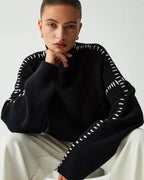 Women's black sweater made from soft knit fabric, featuring contrasting white stitch detail and a relaxed fit design.