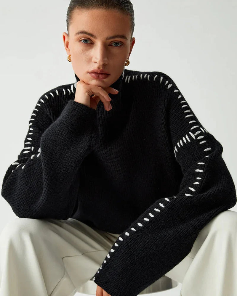 Women's black sweater made from soft knit fabric, featuring contrasting white stitch detail and a relaxed fit design.