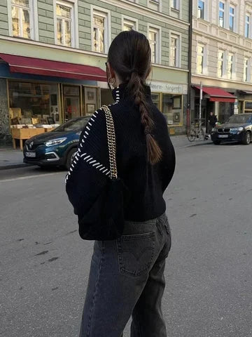 Women's black sweater made of soft knit fabric, featuring white stitch detail for a stylish contrast and comfortable fit.
