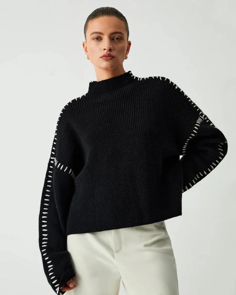 Women's black sweater made of soft fabric, featuring white stitch detail along the neckline and sleeves for a stylish touch.