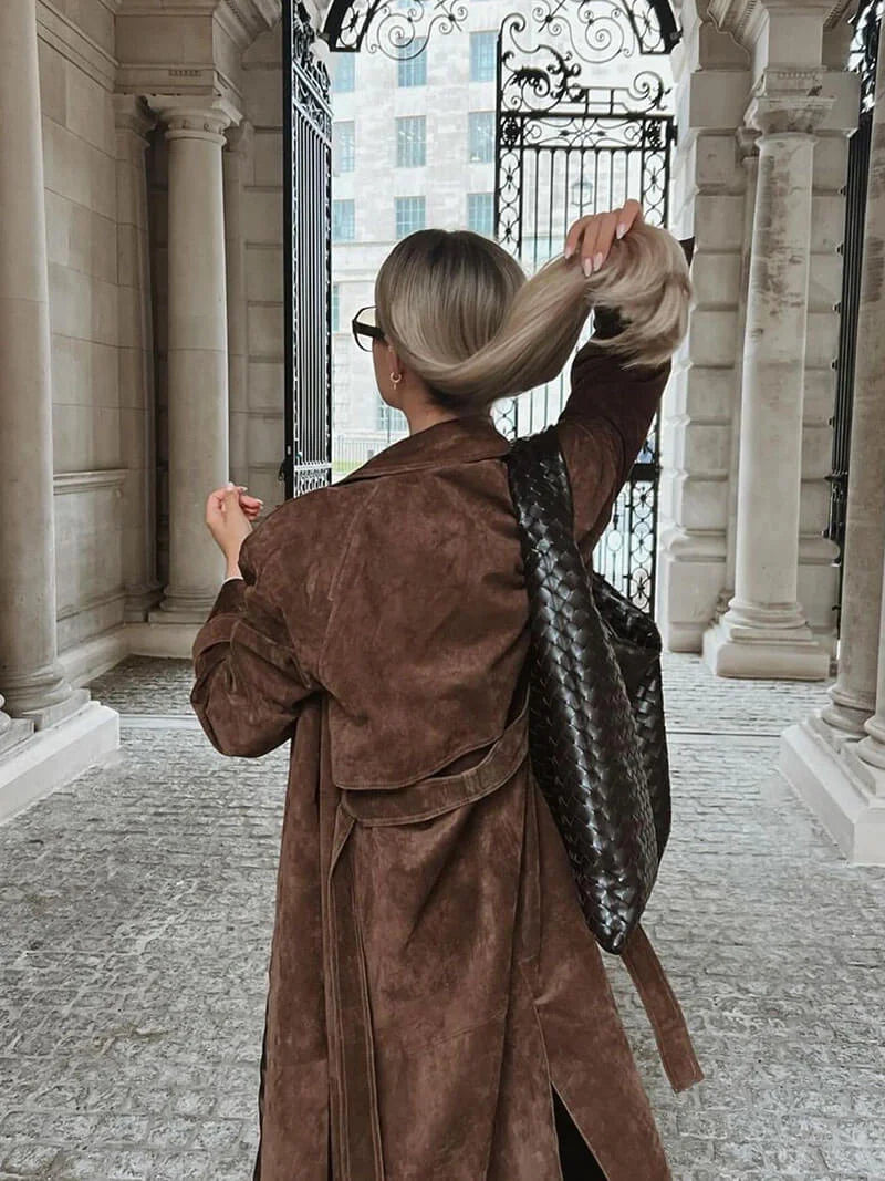 Women's brown trench coat made of durable fabric, featuring a belted waist, classic lapels, and a mid-length silhouette.