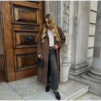 Women's brown trench coat made of durable fabric featuring wide lapels and a tie waist for a flattering silhouette.