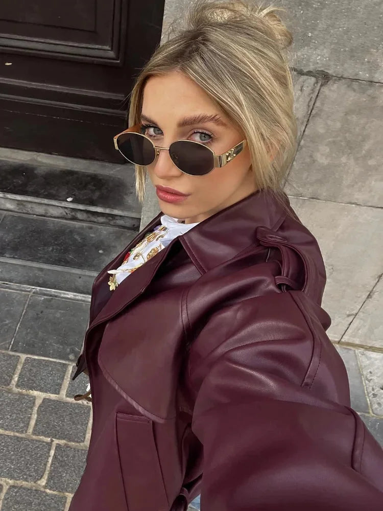 Women's burgundy short belted trench coat in durable cotton blend, featuring a classic design with a stylish tie waist…
