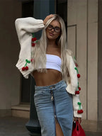 Women's cream cardigan with long sleeves, featuring intricate cherry embroidery, made from soft, breathable fabric.