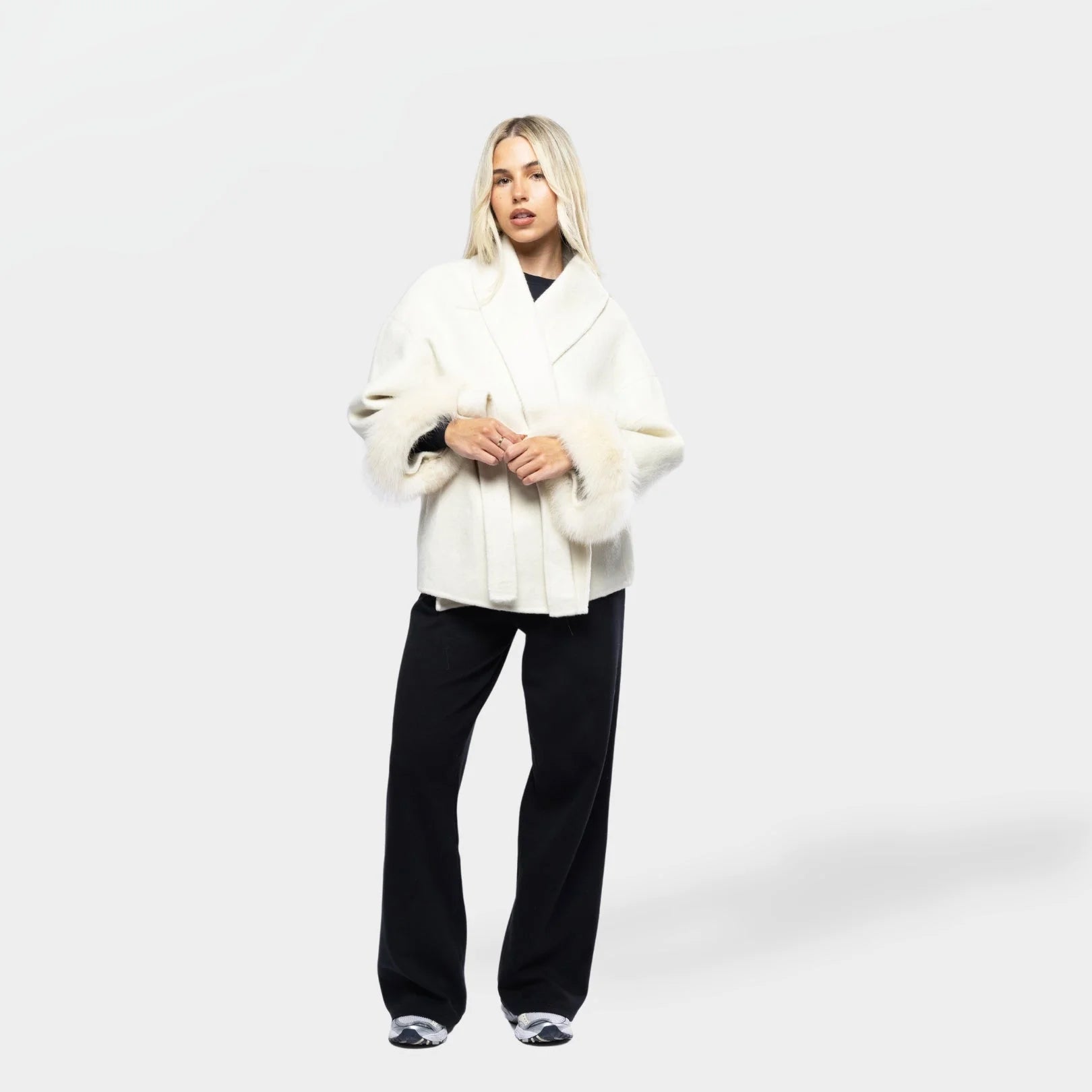 Women's cream jacket with a tie belt, featuring soft fur cuffs and a stylish design, perfect for layering in cooler weather.