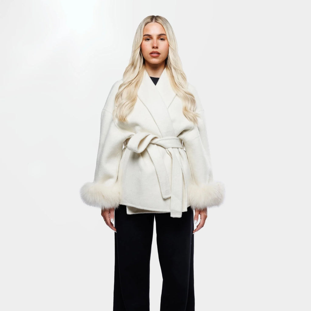 Women's cream jacket made of soft fabric, featuring a tie belt and stylish fur cuffs for added warmth and texture.