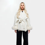 Women's cream jacket made of soft fabric, featuring a tie belt and stylish fur cuffs for added warmth and texture.