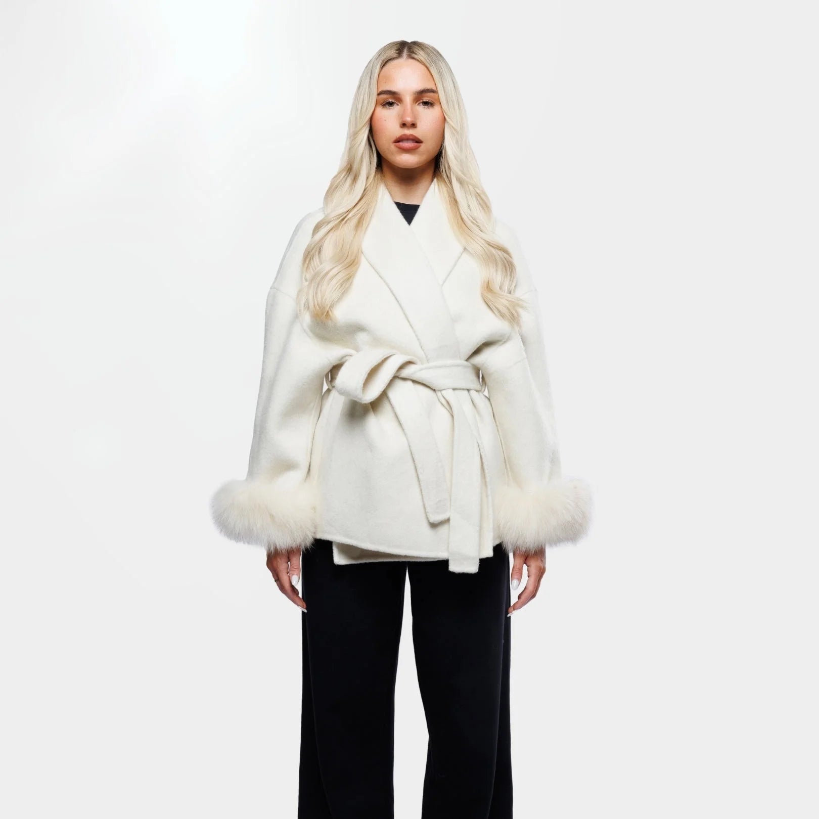 Women's cream jacket made of soft fabric, featuring a tie belt and stylish fur cuffs for added warmth and texture.