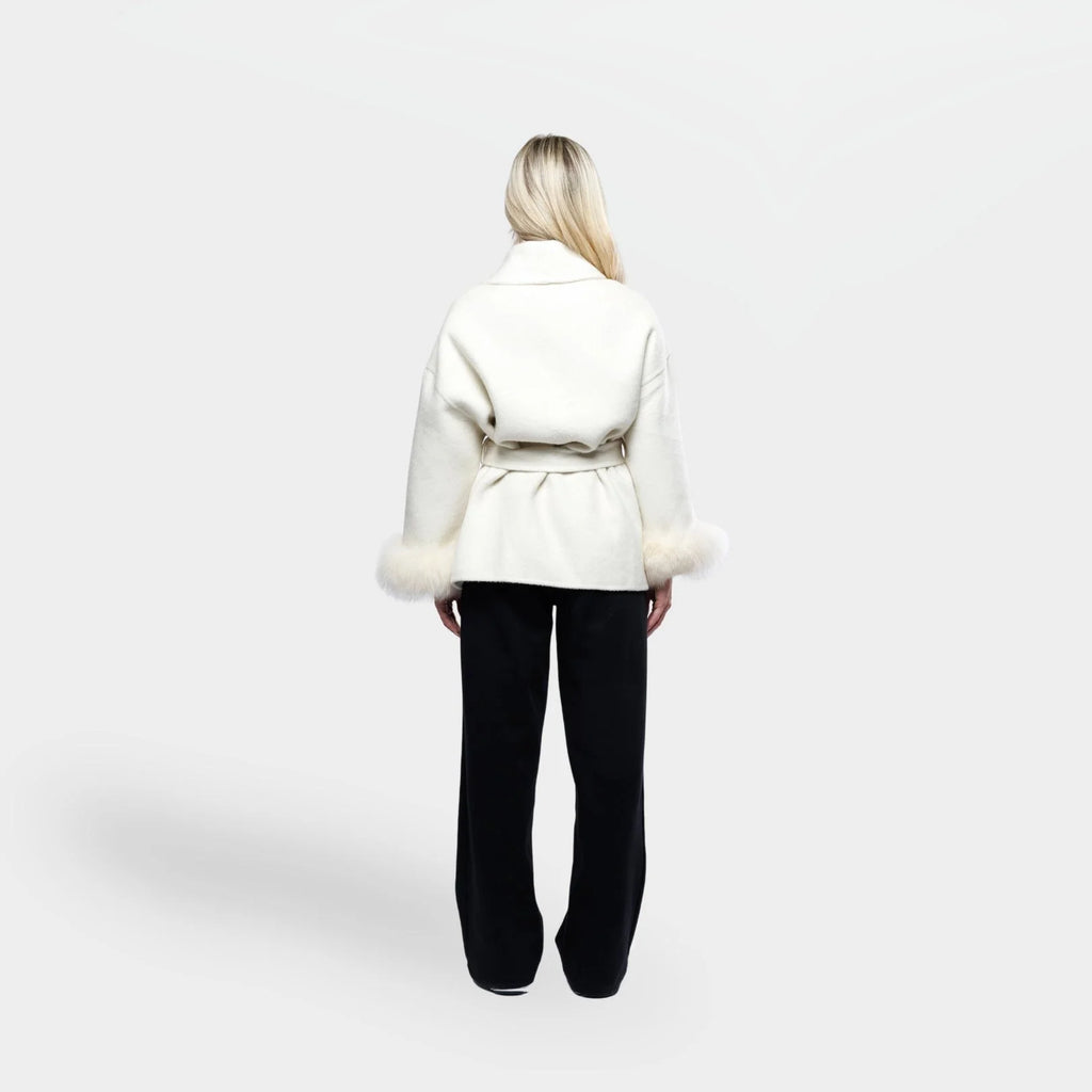 Women's cream jacket with tie belt and fur cuffs, made from soft fabric, featuring a stylish wrap design and warm accents.