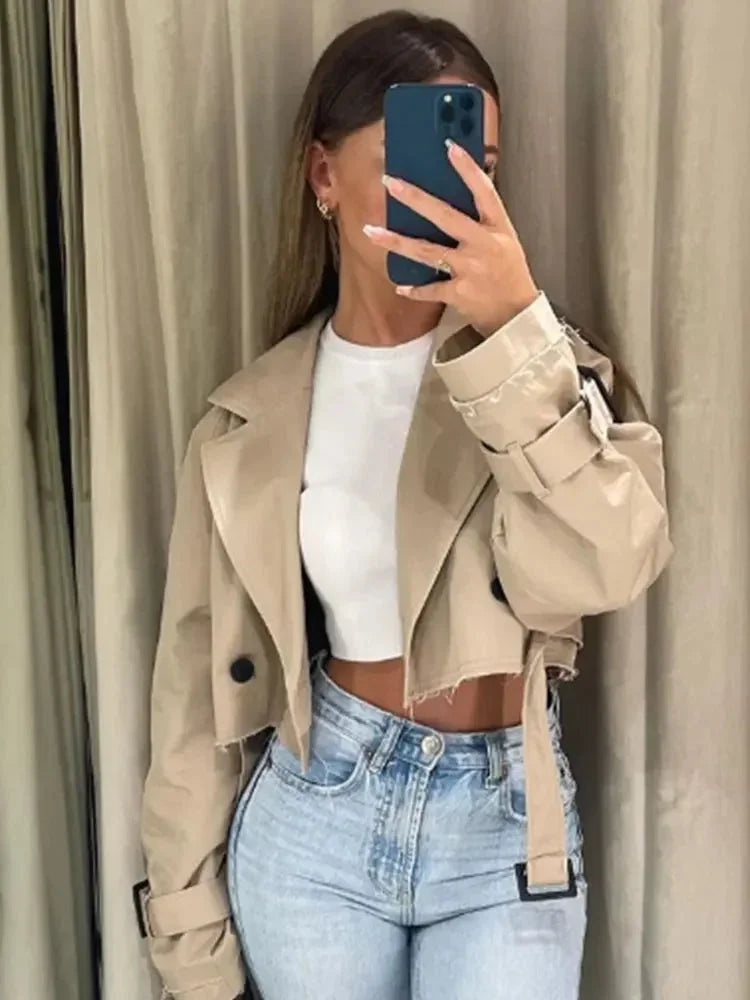 Women's cropped beige trench coat featuring long sleeves, made from lightweight fabric with a classic double-breasted design.