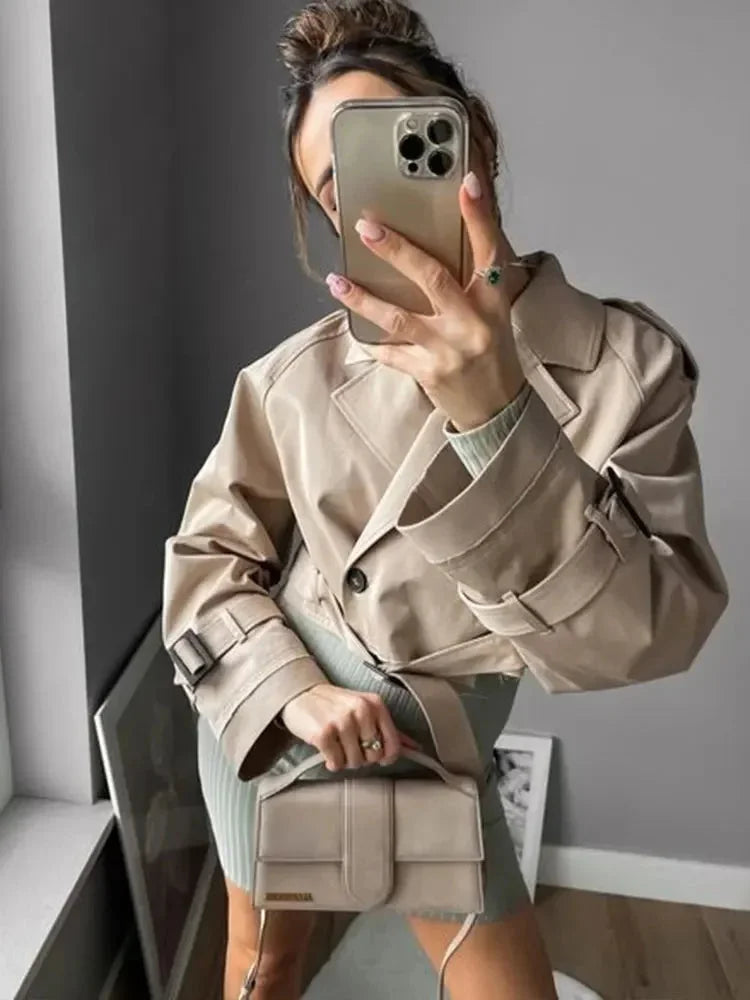 Women's cropped beige trench coat made of lightweight cotton, featuring long sleeves and classic double-breasted design.