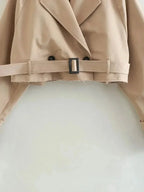 Beige cropped trench coat for women, featuring long sleeves and a classic belted design, made from lightweight fabric.