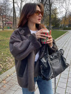 Women's dark brown faux shearling coat featuring wide lapels and a soft, textured finish for warmth and style.