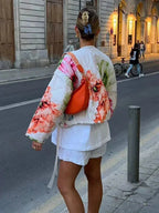 Women's floral bomber jacket made from lightweight fabric, featuring drawstring details and a vibrant floral pattern.