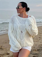 Women's loose-fit knitted sweater made of soft cotton blend, featuring a relaxed design and ribbed cuffs for comfort.