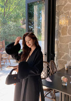 Women's long belted coat featuring faux fur cuffs, made of soft fabric for warmth and a stylish silhouette.
