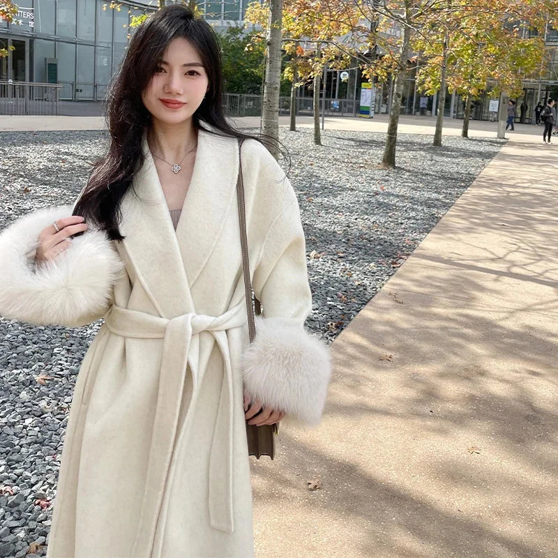 Women's long belted coat featuring soft fabric and faux fur cuffs for added warmth and style in a classic silhouette.