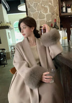 Women's long belted coat featuring faux fur cuffs, crafted from warm fabric for style and comfort in cooler weather.