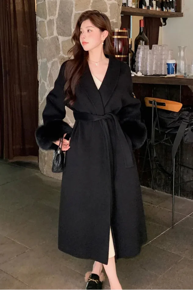 Women's long belted coat featuring soft faux fur cuffs and a classic silhouette, perfect for layering in cooler weather.