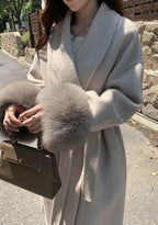 Women's long belted coat featuring faux fur cuffs, crafted from soft fabric for warmth and stylish comfort in cooler weather.