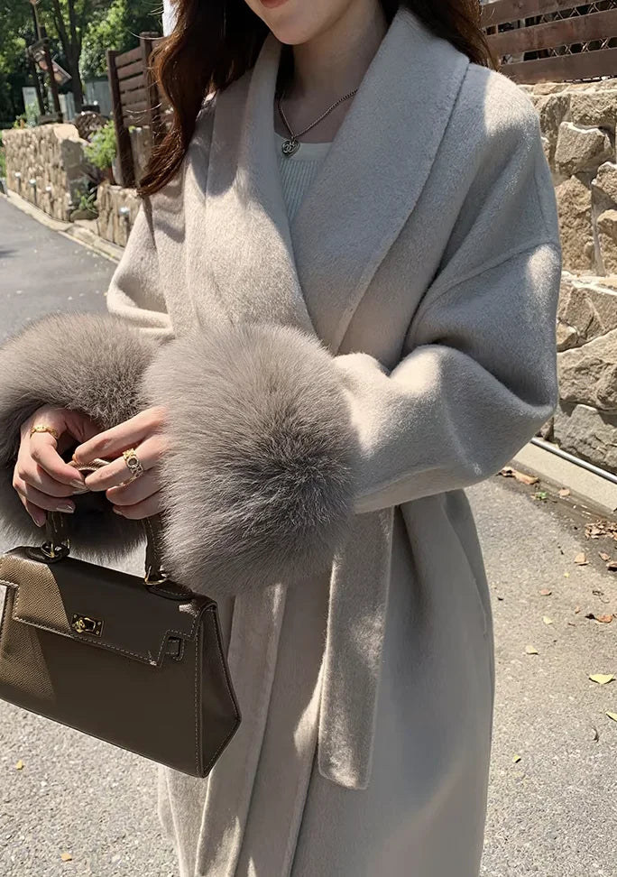 Women's long belted coat featuring faux fur cuffs, crafted from soft fabric for warmth and stylish comfort in cooler weather.