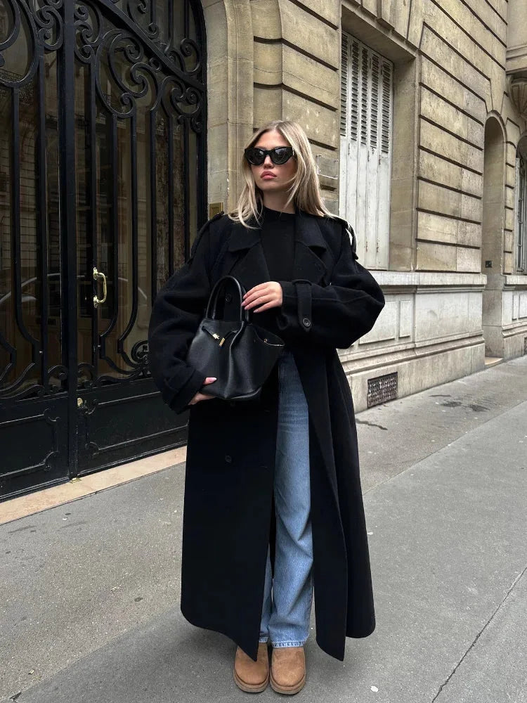 Women's long black coat made from soft fabric, featuring a belt, wide lapels, and a tailored silhouette for a stylish look.