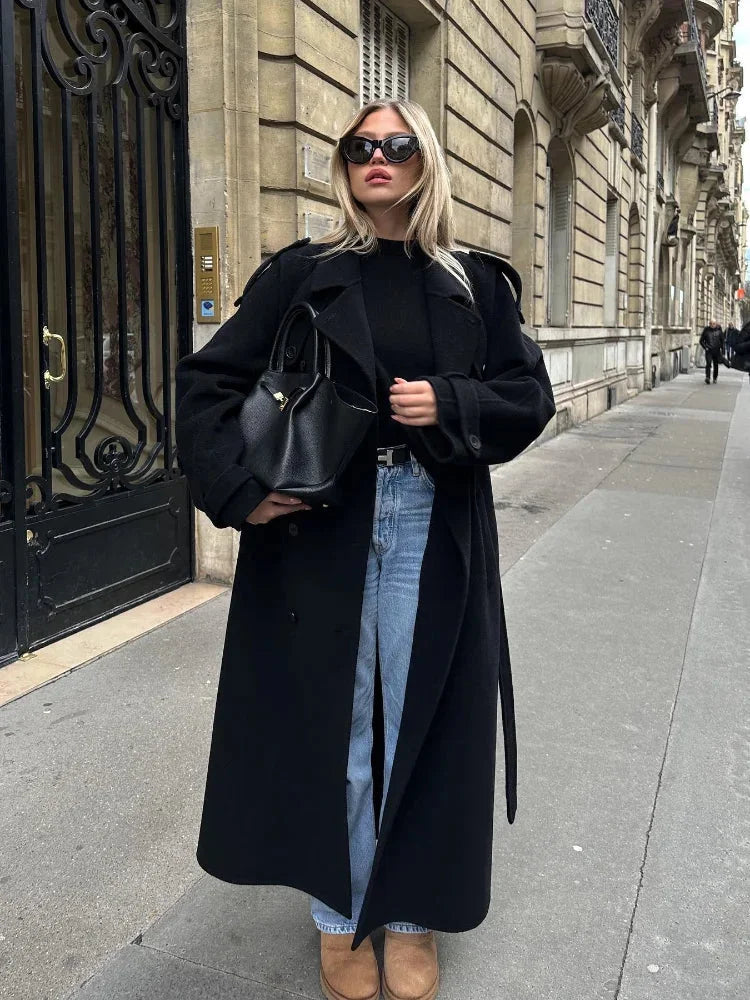 Black long coat for women featuring a belted waist, wide lapels, and crafted from soft, warm fabric for stylish layering.