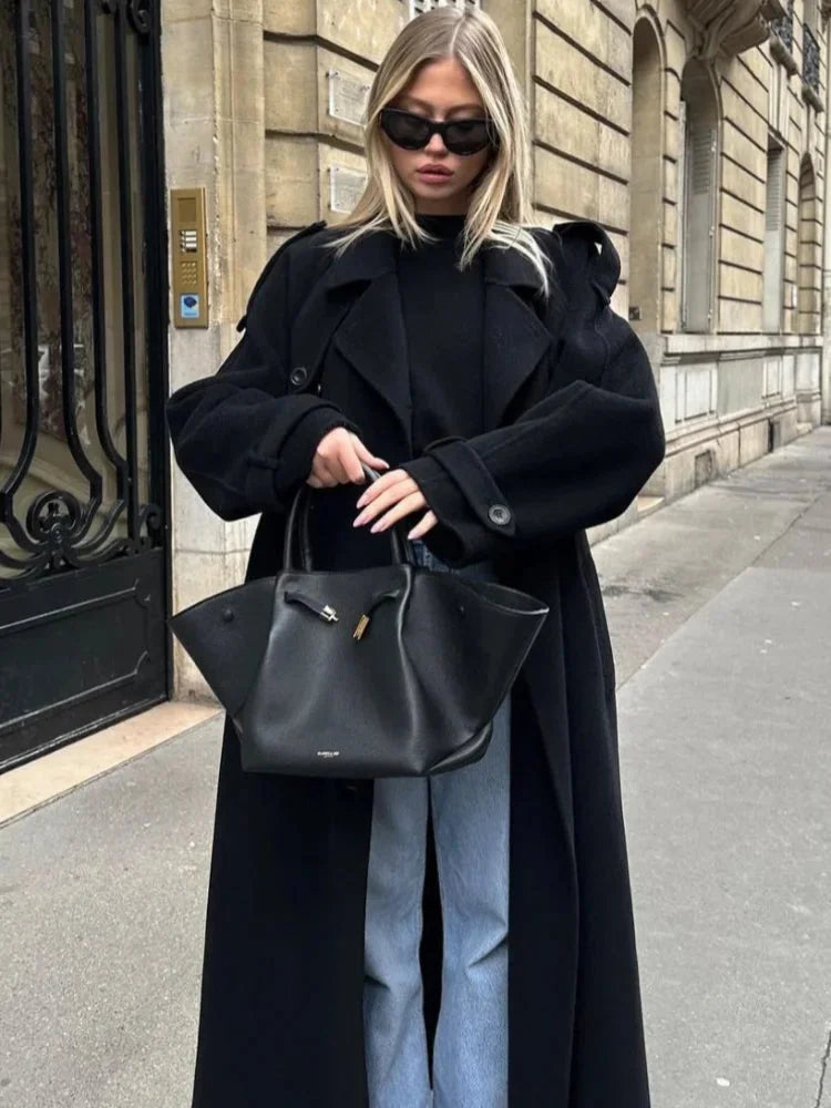 Women's long black coat made of soft fabric, featuring a belted waist and wide lapels for a stylish, tailored fit.