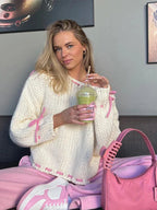 Women's off-shoulder knitted sweater in soft yarn featuring stylish ties for a trendy look and comfortable fit.