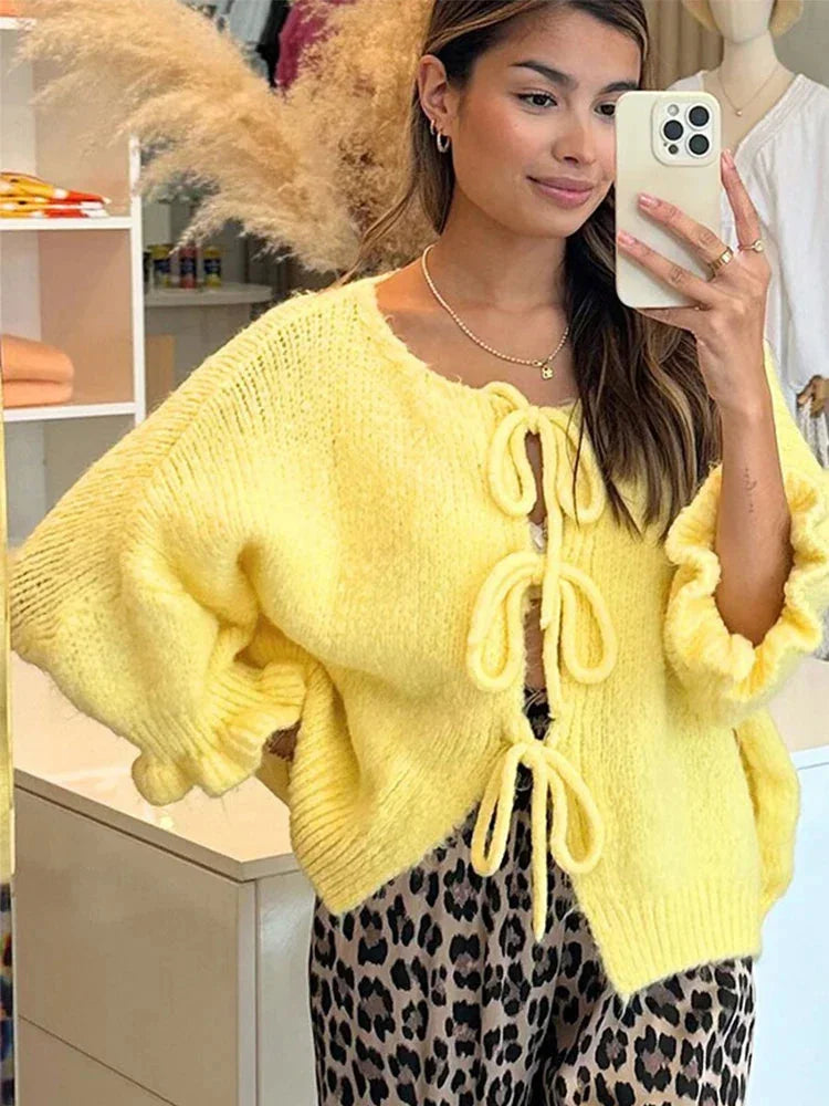 Women's open-front yellow cardigan made of soft knit fabric, featuring bow tie details on the cuffs for a charming touch.
