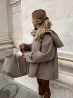 Women's oversized beige coat featuring large buttons, made of soft fabric with a relaxed fit and practical side pockets.