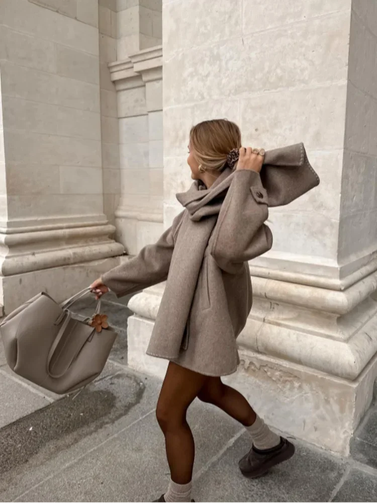 Women's oversized beige coat featuring large buttons, made from a soft fabric with a relaxed fit for comfort and style.