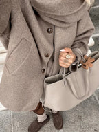 Women's oversized beige coat featuring large buttons, crafted from soft fabric with a relaxed fit perfect for layering.