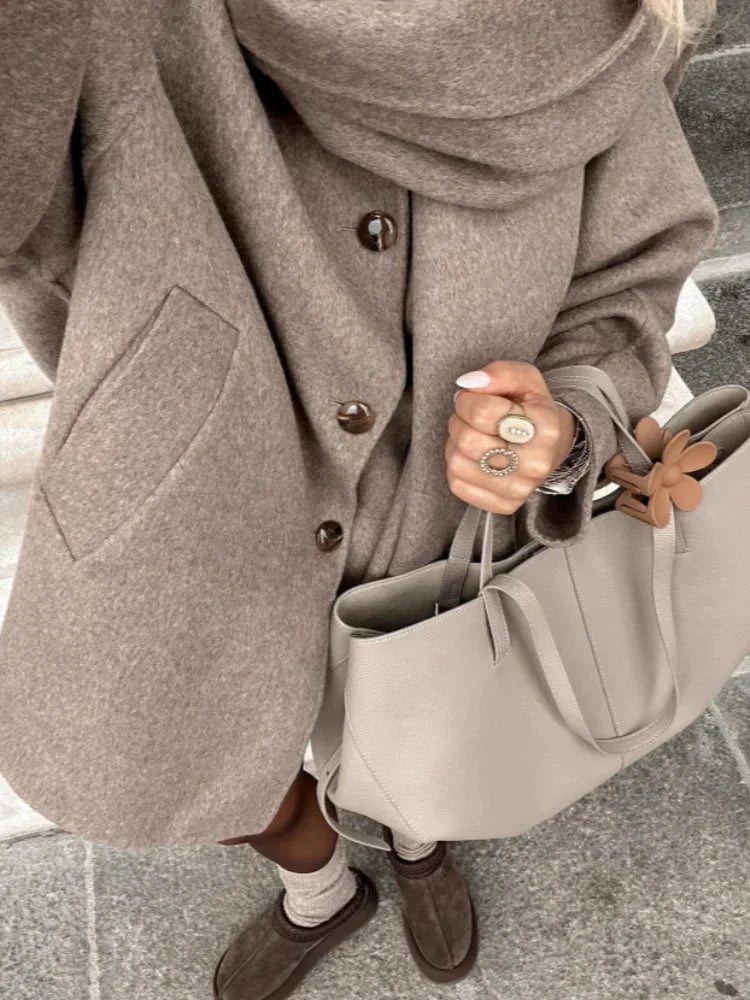 Women's oversized beige coat featuring large buttons, crafted from soft fabric with a relaxed fit perfect for layering.