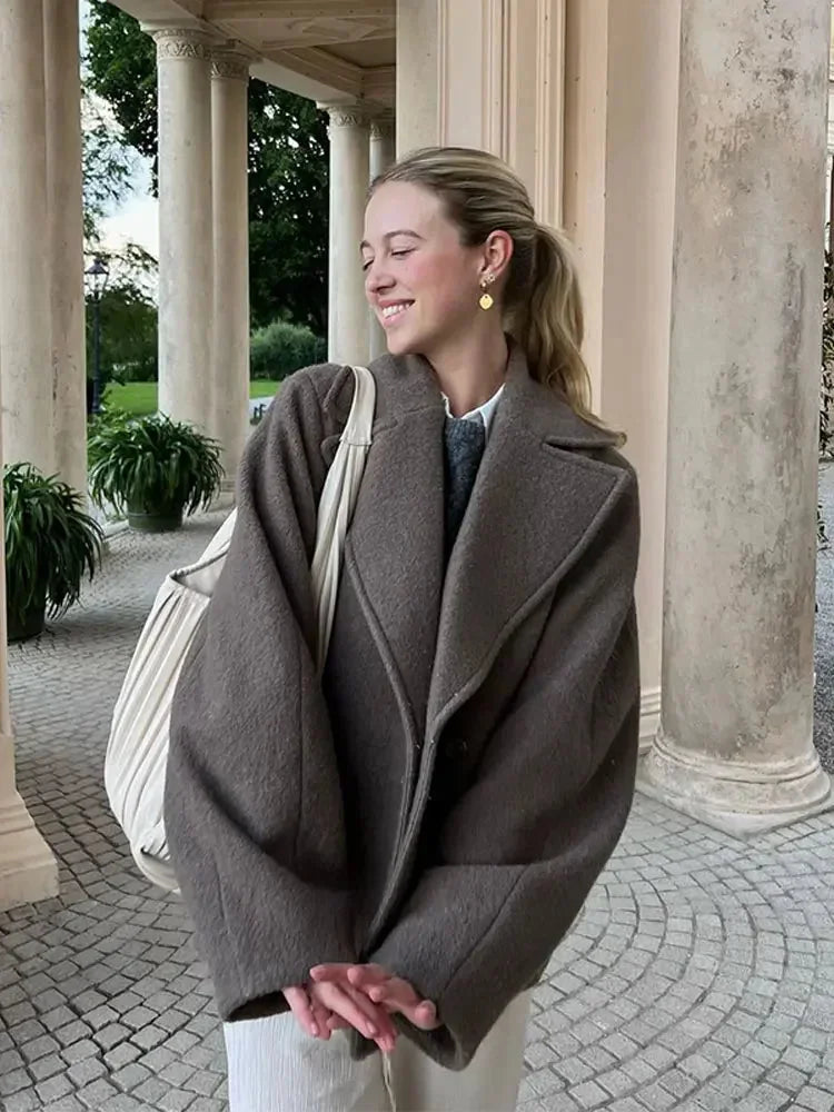 Women's oversized brown jacket featuring a button closure, made from soft fabric with a relaxed fit and front pockets.